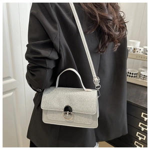 Vue latérale d'un petit sac carré à paillettes argentées sur un modèle avec bandoulière