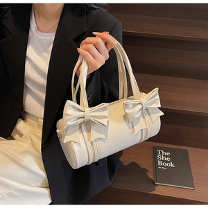 Detail of cream bow-knot barrel handbag with glossy finish and dual handle design