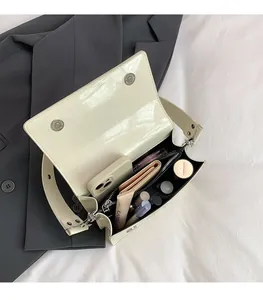 Detail view of large capacity beige patent leather shoulder bag with makeup and smartphone