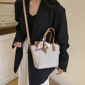 Sac seau tissé beige chic avec bordure en cuir marron et détail de foulard en soie