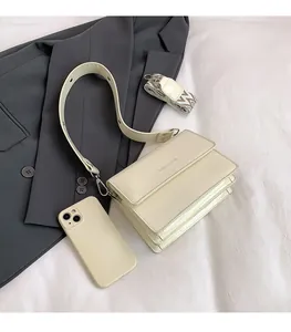 Detail of cream patent leather crossbody bag with dual straps and fashion logo