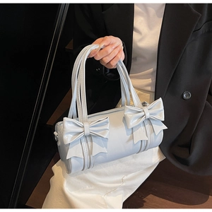 Detail of light blue bow handbag featuring glossy synthetic leather and cylinder shape