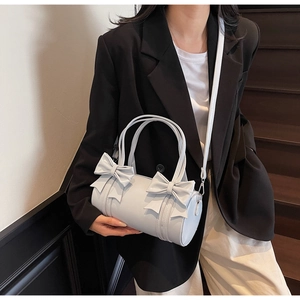 Detail of grey bow-knot pillow bag featuring round handles and leather strap