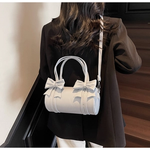 Detailed view of light blue bow pillow bag worn crossbody by a model on stairs