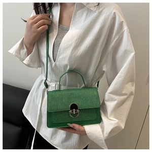 Détail du sac vert montrant la texture pailletée et le fermoir rotatif argenté