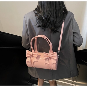Detail of pink patent leather cylinder bag featuring elegant oversized bow decorations