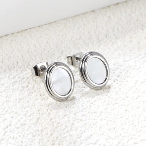 Détail macro de boucles d'oreilles ovales en acier doré 18K et nacre blanche naturelle