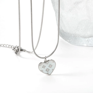 Macro shot of silver heart pendant with clover motif and white inlay on snake chain