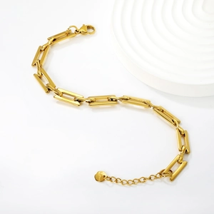 Detailed macro view of gold-tone rectangular link chain bracelet with lobster clasp closure