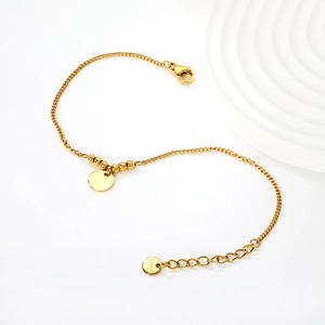 Minimalist gold stainless steel beaded bracelet with a polished round charm on white base