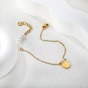 Elegant gold stainless steel pearl bracelet featuring a shell pendant on a white background