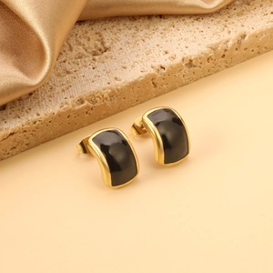 Détail de boucles d'oreilles vintage dorées avec émail noir sur pierre de travertin