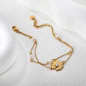 French double-layer gold sunflower bracelet with elegant pearls on a white stone background