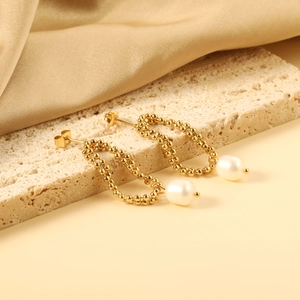 Close-up of golden beaded chain earrings with elegant white pearls on a silk background