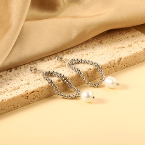 Close-up of double-layered silver bead chain earrings with white pearls on silk background