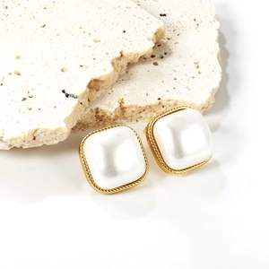 Square vintage pearl earrings with gold braided edges on a minimalist stone display