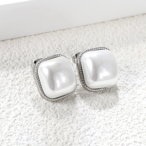 Detail of square silver earrings with white pearl inlay and twisted rope metal borders