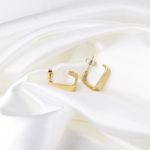 Boucles d'oreilles créoles carrées en C évidées en or 14K sur satin blanc soyeux