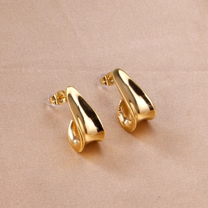Detailed view of polished golden J-shaped irregular curved earrings on soft satin fabric