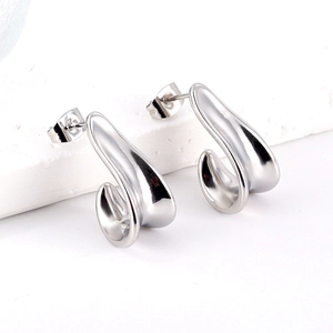 Polished silver stainless steel J-shaped curved earrings on a white stone pedestal