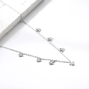 Dettaglio di ciondoli a corona in argento su una catena a maglie fini su fondo bianco