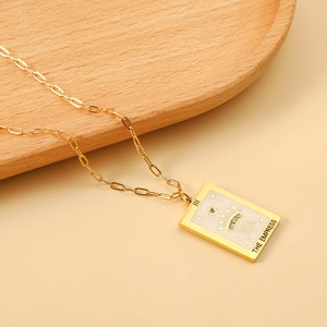Close-up of gold rectangular The Empress tarot card necklace with a crown and star pendant