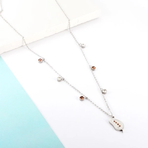 Macro detail of silver necklace chain with tiny round gems and leaf-shaped pendant charm
