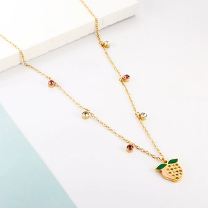 Detailed view of peach fruit pendant with purple rhinestones on a gold-plated chain