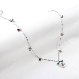Macro shot of silver strawberry pendant necklace with colorful rhinestones on fabric