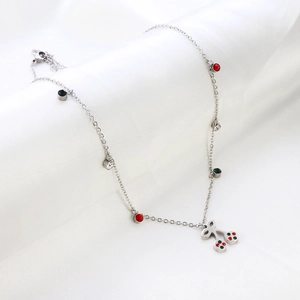 Detail of silver cherry pendant necklace with colorful crystals on a white fabric background