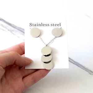 Détail du collier en acier inoxydable argenté avec pendentifs disques sur carte