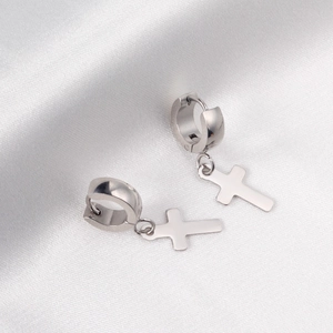 Boucles d'oreilles créoles avec pendentif croix en acier poli sur tissu de soie blanc