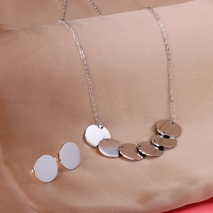 Détail de l'ensemble collier et boucles d'oreilles ronds en métal poli sur soie