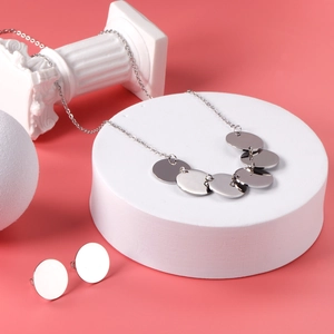 Ensemble collier et boucles d'oreilles argentés avec disques polis sur décor minimal