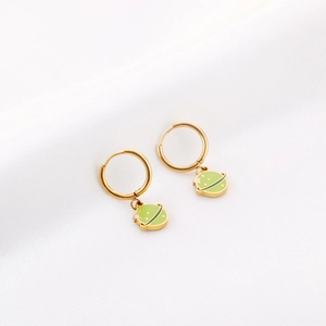Détail de boucles d'oreilles planète en métal doré avec émail vert clair et étoiles