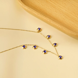 Dettaglio della collana placcata oro 18K con sette ciondoli a fiore e cristalli blu