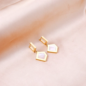 Golden geometric earrings with white mother of pearl inlay on soft pink silk background
