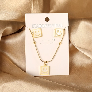 Detail of square white shell earrings and necklace set with minimalist smiley face