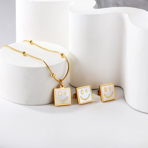 Detail of square white shell earrings and necklace set with golden smiley face design