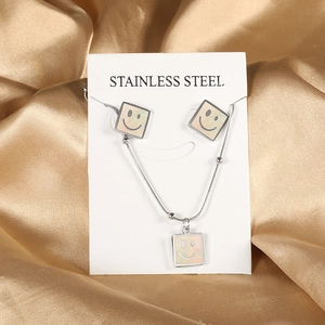 Detail of square smiley face pendants with white shell inlay on stainless steel jewelry set