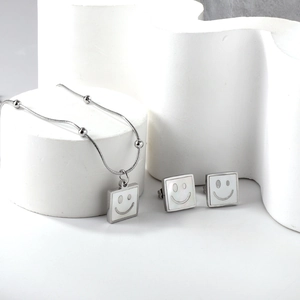 Close-up of square white shell necklace and earrings set with a minimalist smiley face