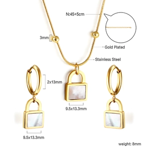 Detailed view of gold plated padlock pendants with white shell inlay on jewelry set