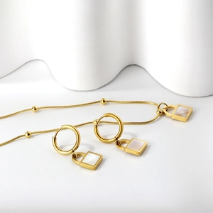 Macro detail of golden stainless steel square white shell pendant necklace and earrings