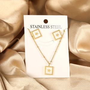 Golden stainless steel jewelry set with square star charms on silk background