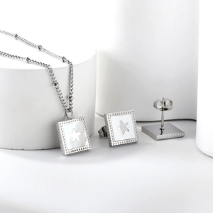 Detail of silver square shell necklace and star earrings set on a white platform