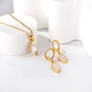 Detailed view of gold necklace and shell earrings on white geometric stands