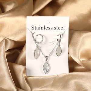 Detail of stainless steel jewelry set with white shell stones on gold satin background