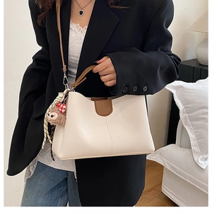 Détail du sac seau en cuir grainé blanc cassé avec poignée marron et pendentif