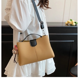 Détail d'un sac seau en cuir jaune moutarde avec charm ours et bandoulière noire chic