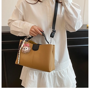Détail du sac seau marron avec motif litchi, charm en peluche ShellieMay et décoration ruban